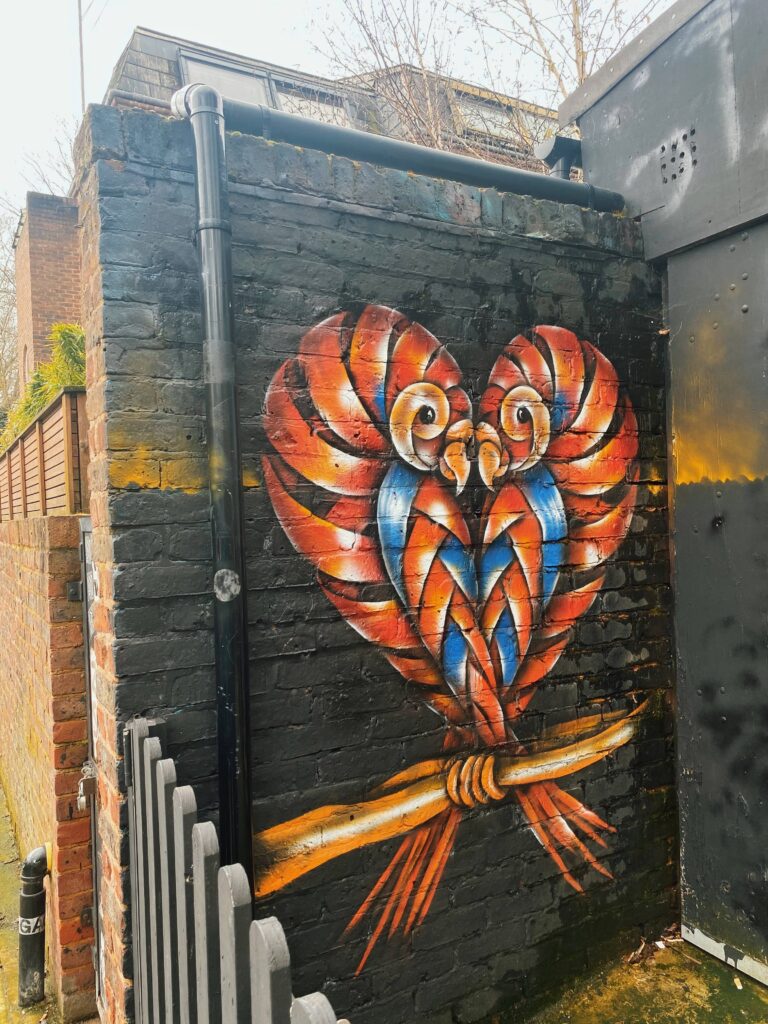 2 birds making a love heart street art on Hawley Street in Camden