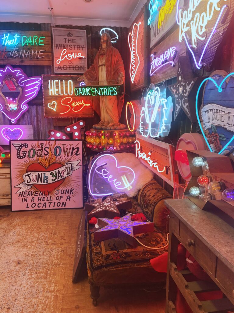 A room with neon signs on the walls at God's Own Junkyard in London