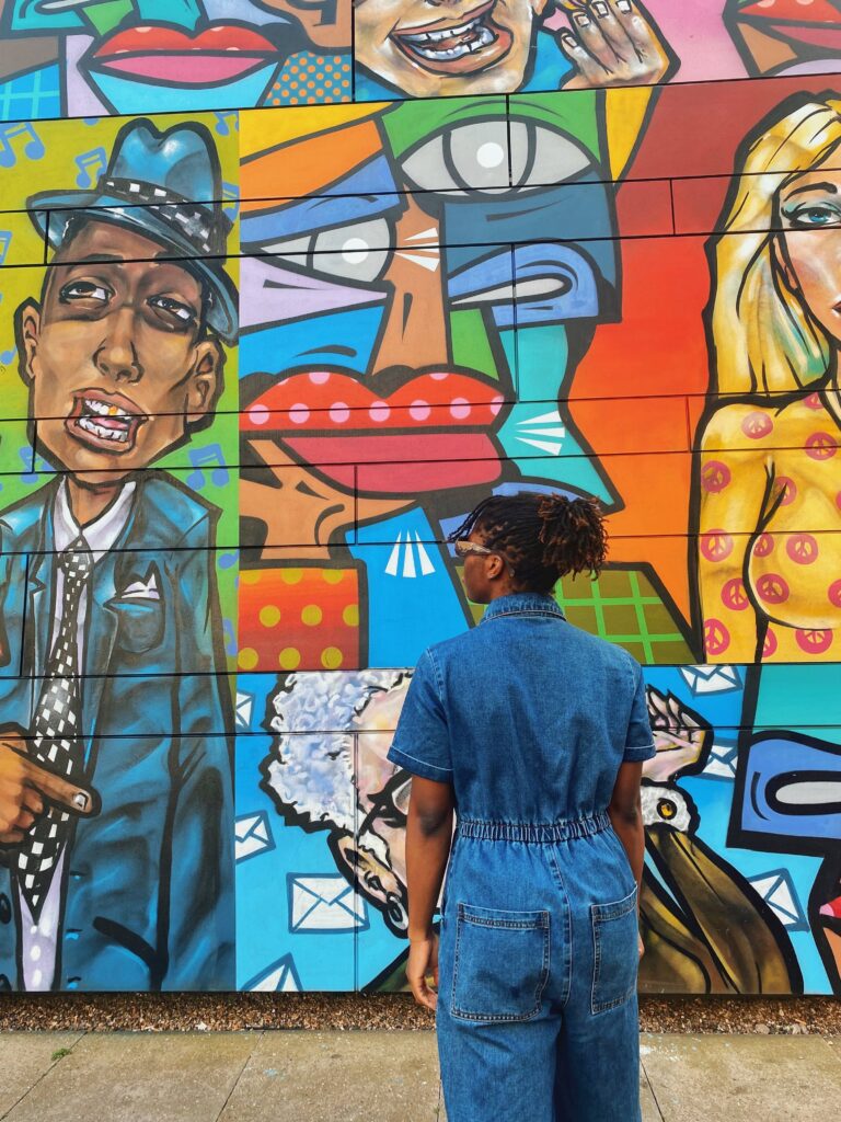 Abigail is looking at street art in Shoreditch, London with her back to the camera