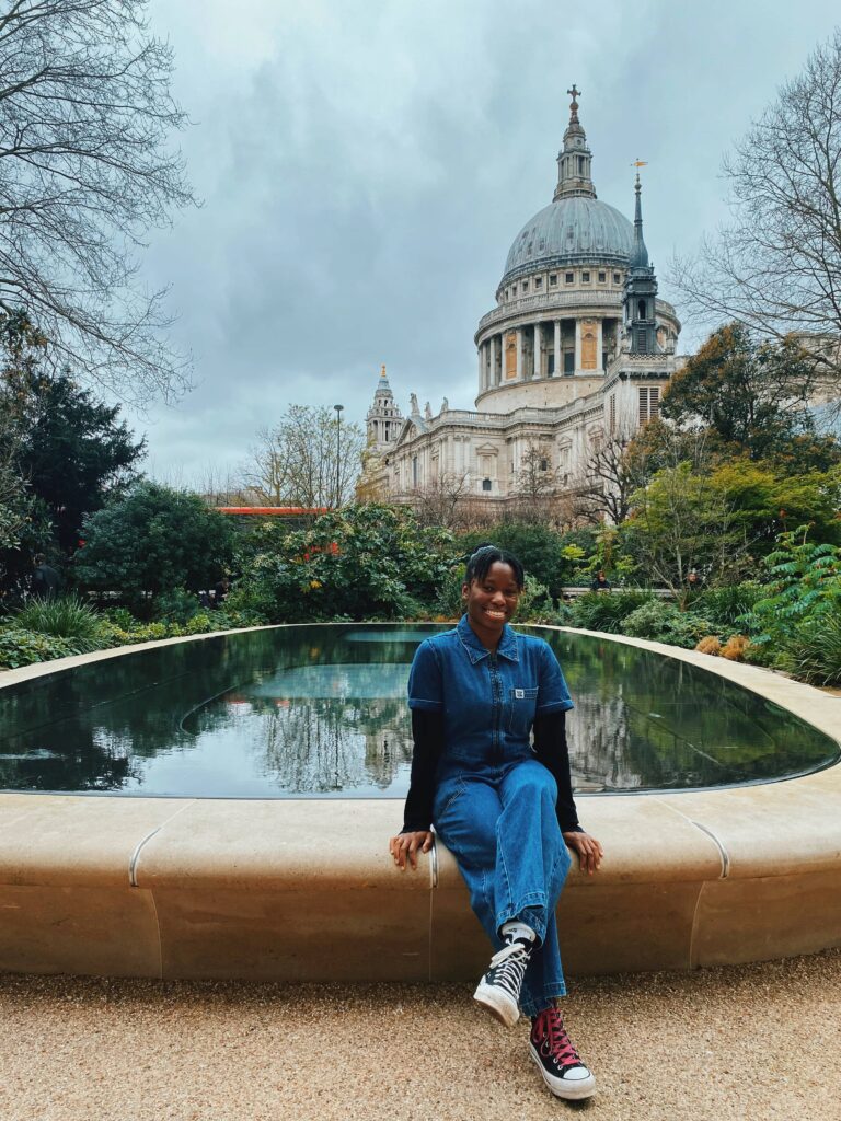 Abigail sitting on the edge of a garden pool with St Paul's Cathedral in the backdrop