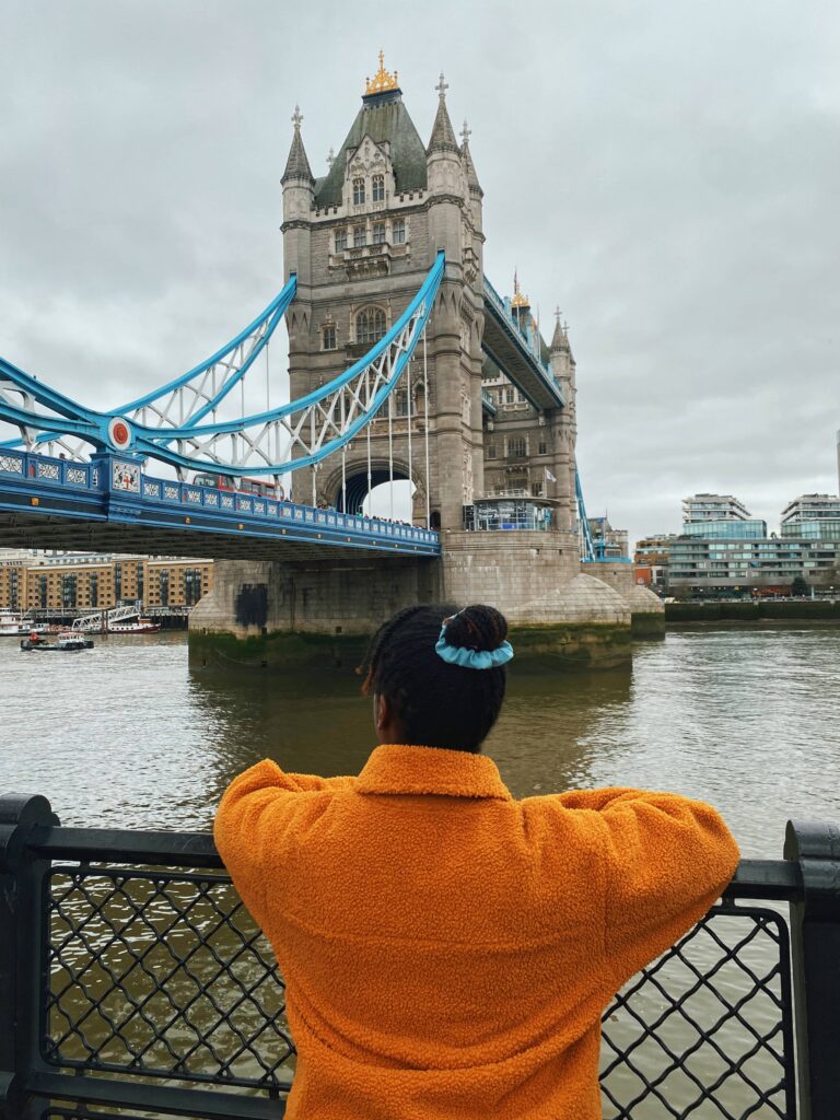 Abigail looking at Tower Bridge in London on the riverbank 